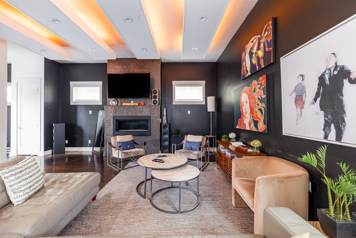 Living room with orange-lit tray ceiling, fireplace and music art